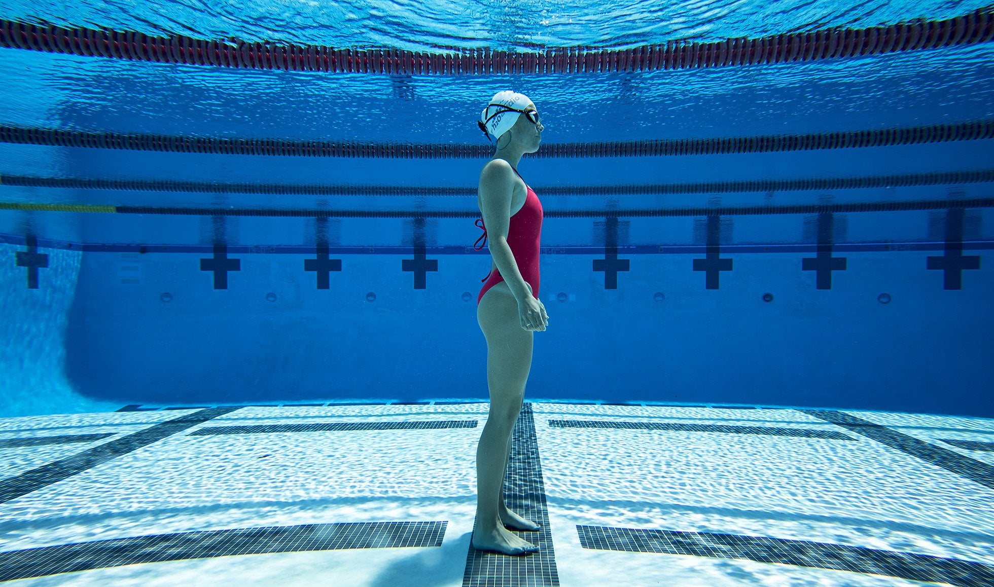 The H2O Audio STREAM is a waterproof MP3 player for swimming. This image shows a female swimmer in a swimming pool using the STREAM MP3 player with waterproof headphones. 