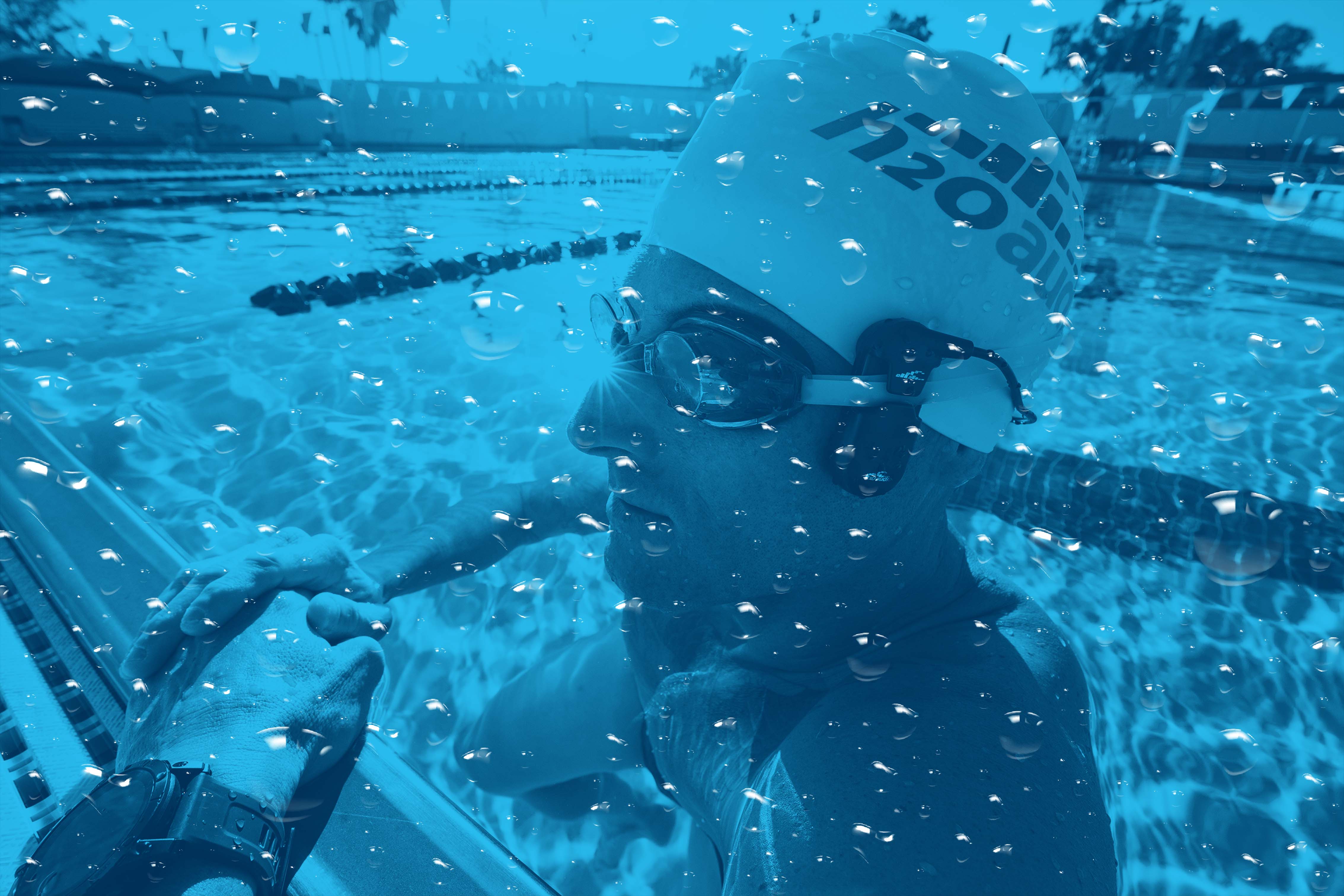 person in a pool wearing swimming headphones located on the h2o audio waterproof headphones homepage