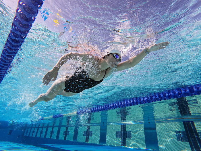 a woman swimming underwater in a pool